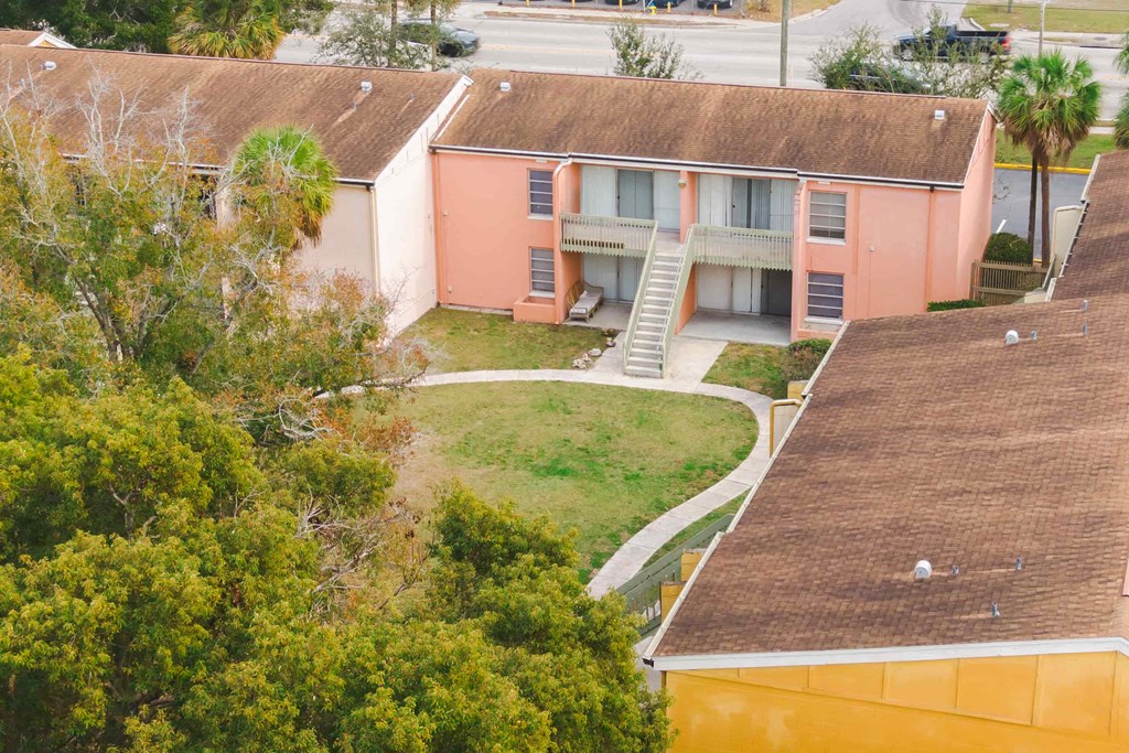 an aerial view of a pink house with a yard and trees