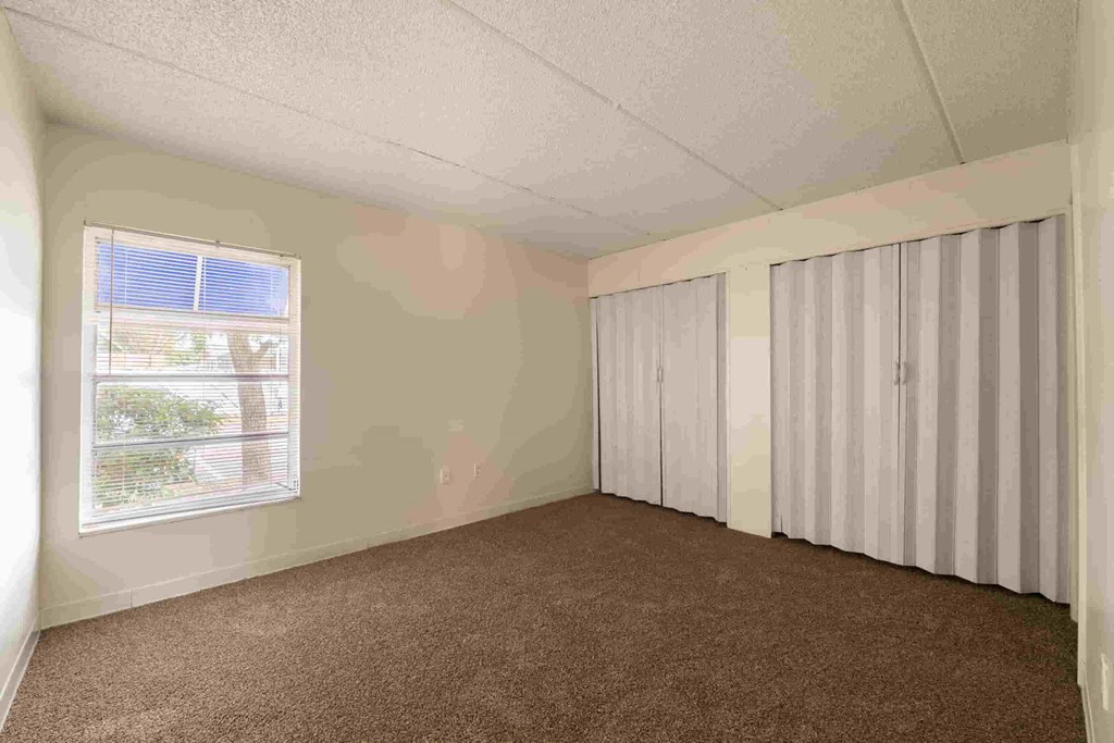 an empty bedroom with two closets and a window