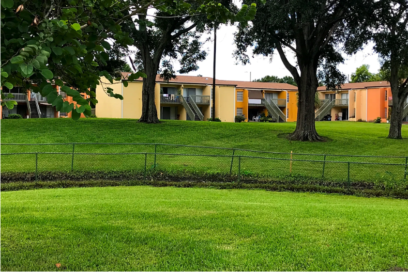 a grassy field with trees and a building in the background