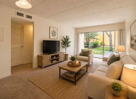 A living room with a flat screen TV and a large window.