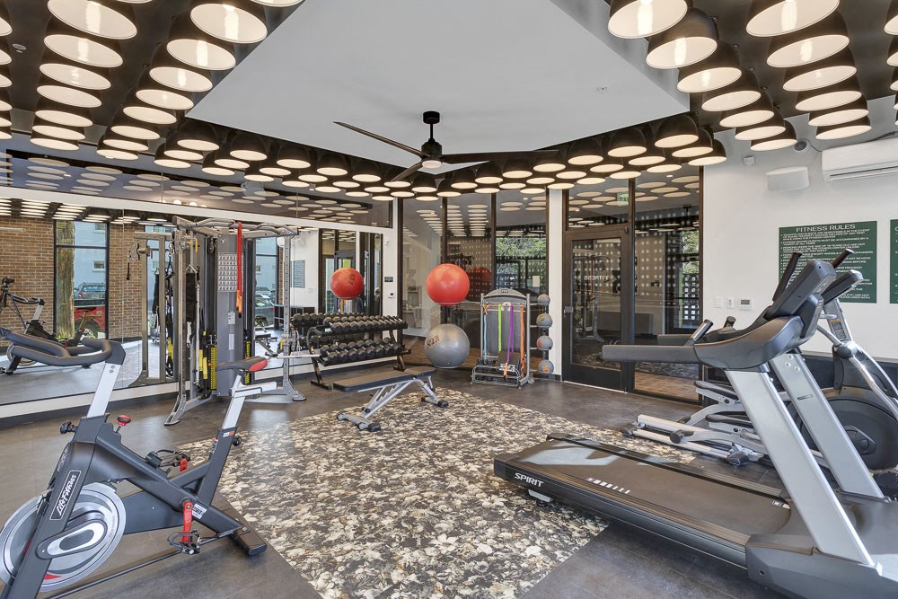 a gym with exercise equipment and a ceiling fan