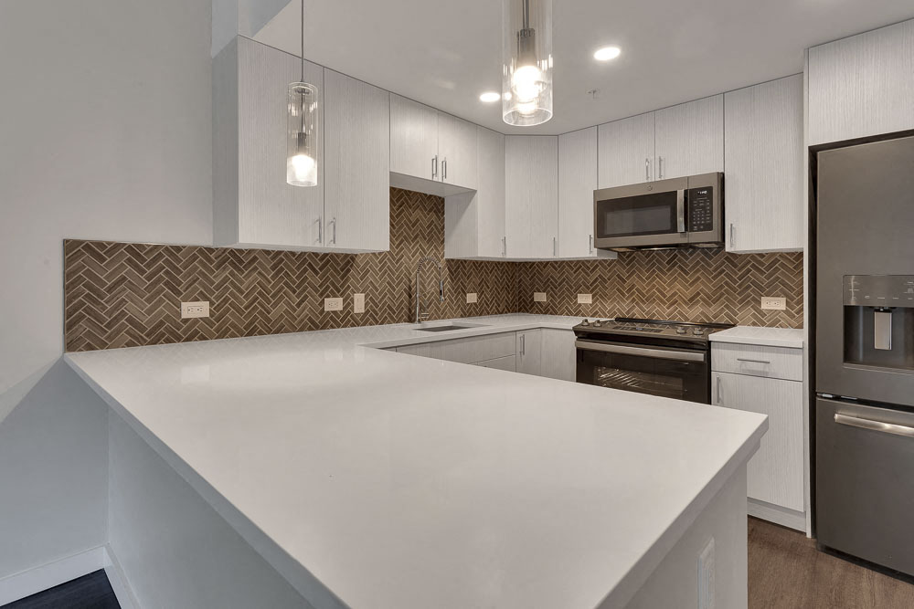 an empty kitchen with a white counter top