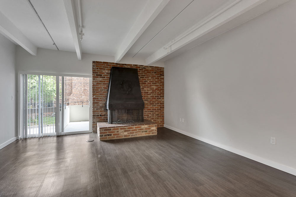 an empty living room with a fireplace and a sliding glass door