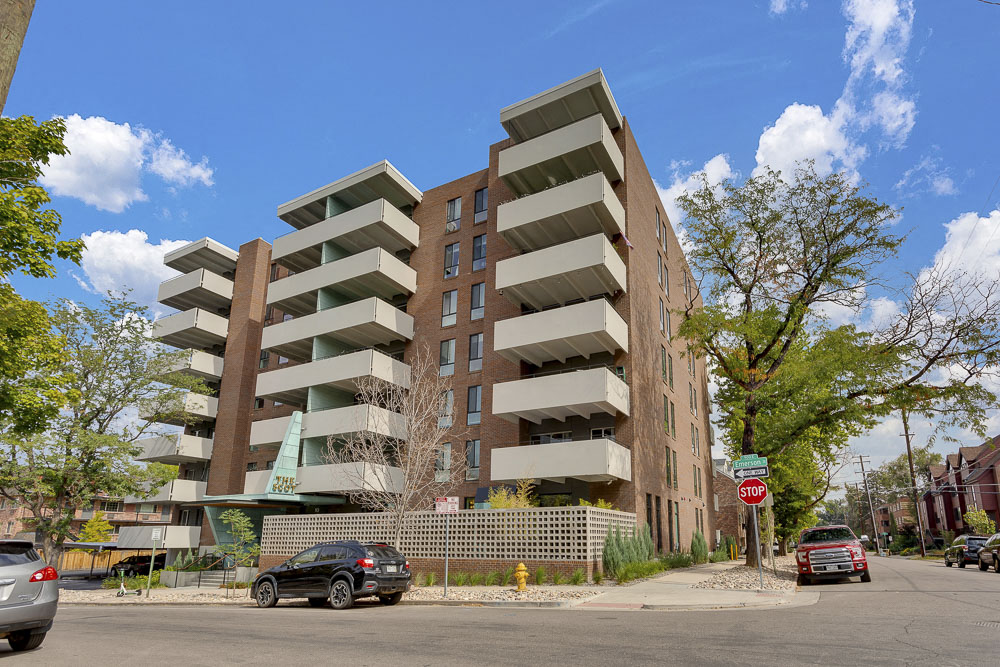 an apartment building on the corner of a street with cars