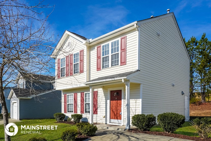 a white house with red shutters and a red front door