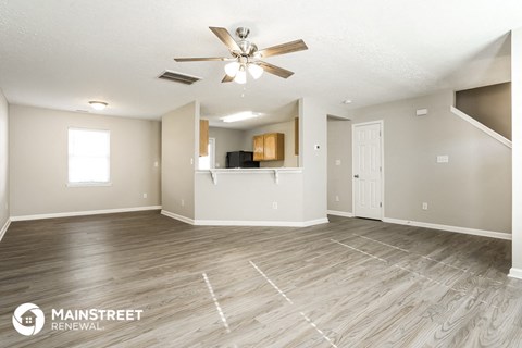 a living room with a ceiling fan and a kitchen