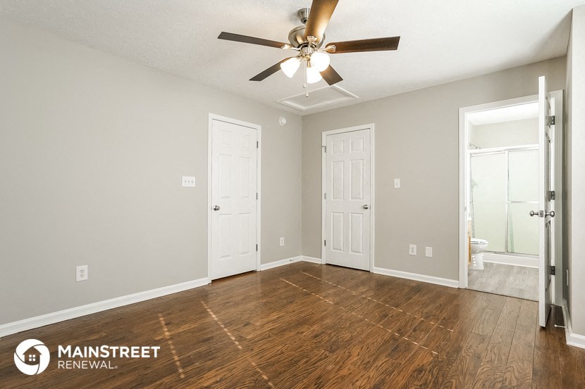 the spacious living room with wood flooring and a ceiling fan