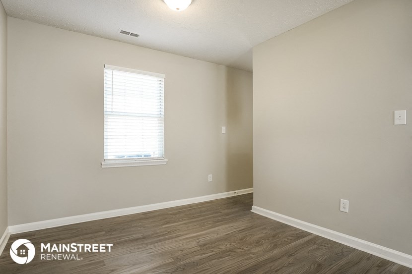 the spacious living room with wood flooring and a window