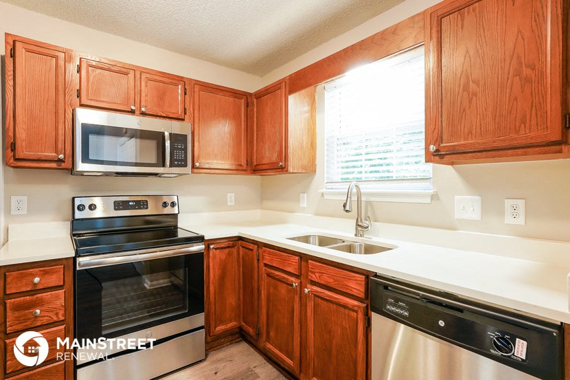 a kitchen with wooden cabinets and stainless steel appliances and a window