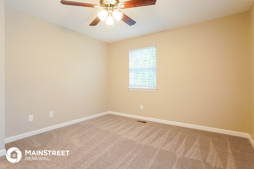 the master bedroom has a carpeted floor and a ceiling fan
