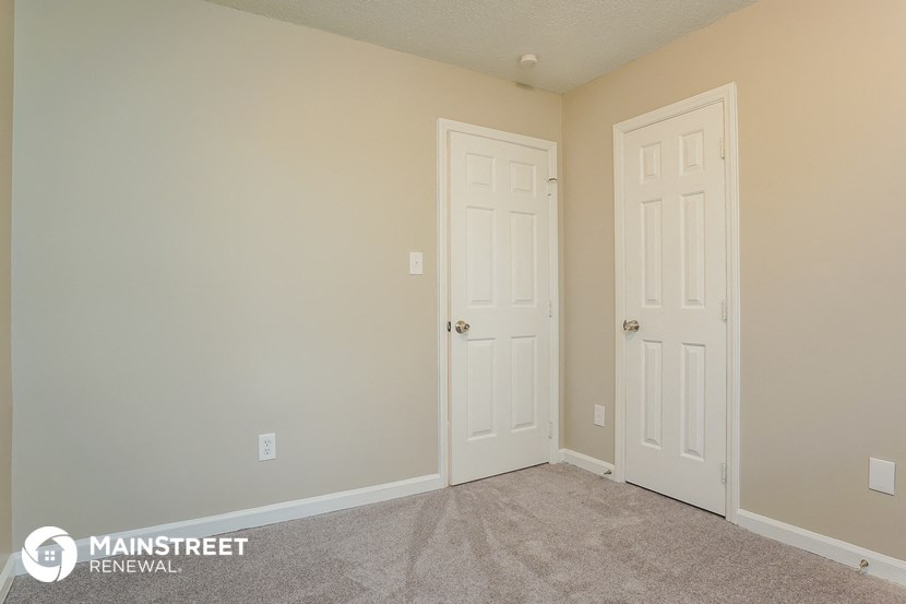 a bedroom with two doors and a carpeted floor