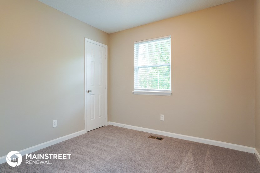 a room with carpet and a white door and a window