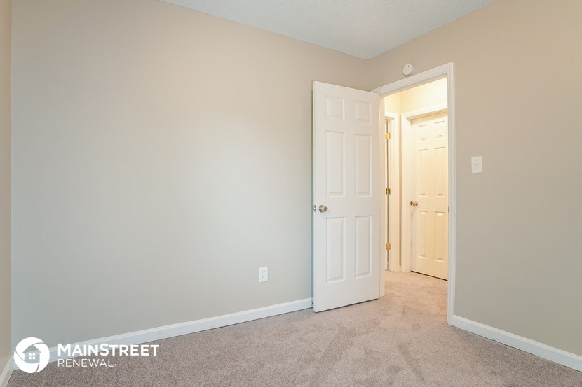 a bedroom with a white door and a hallway to a closet