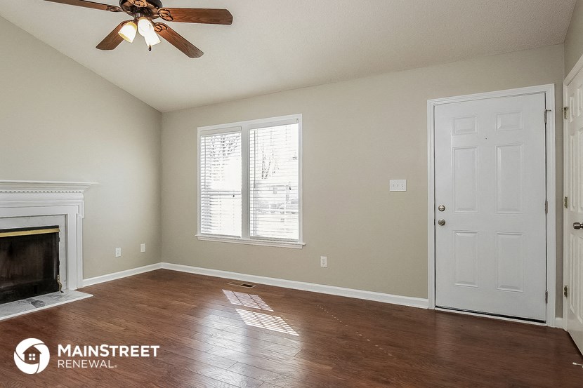 a living room with a fireplace and a ceiling fan