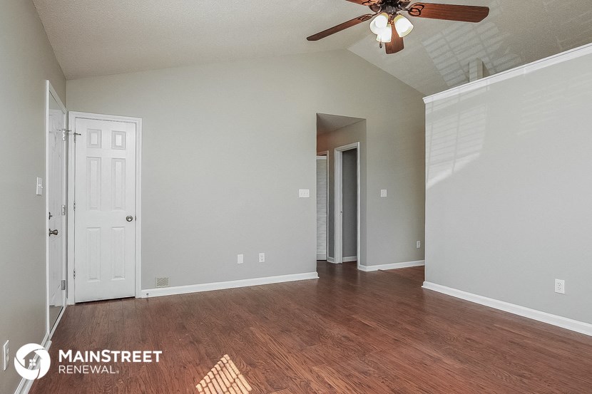 an empty living room with wood floors and a ceiling fan