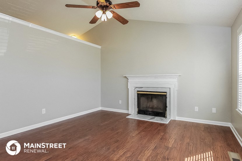 the living room with fireplace and ceiling fan