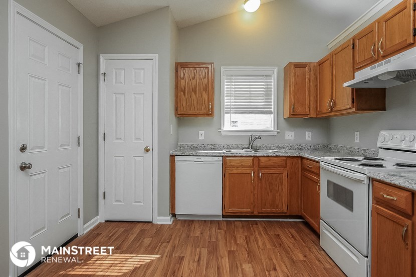 a kitchen with wood flooring and white appliances and wooden cabinets