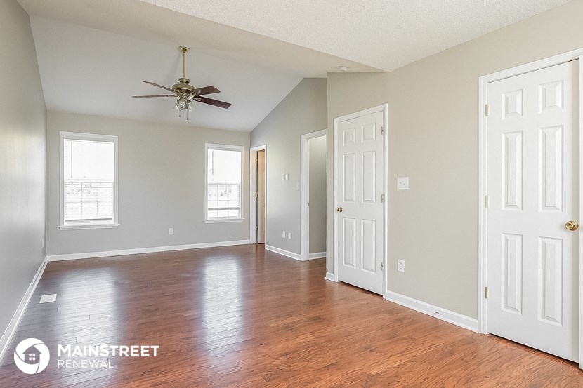 an empty living room with wood floors and a ceiling fan