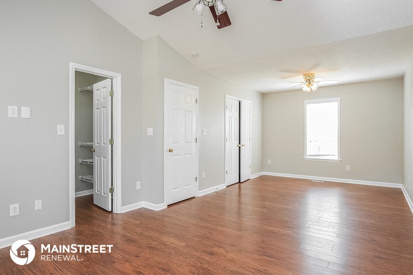 an empty living room with wood floors and a ceiling fan