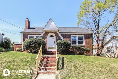 a small brick house with a white door and a staircase