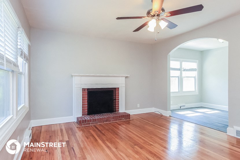 an empty living room with a fireplace and a ceiling fan