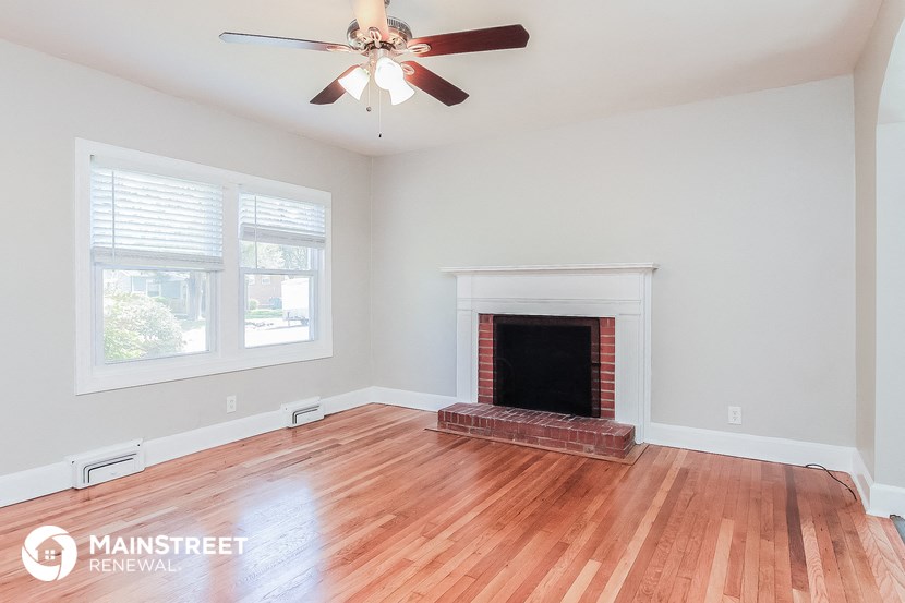 the living room with wood floors and a fireplace