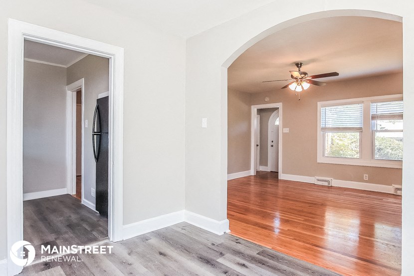 an empty living room with wood floors and a ceiling fan