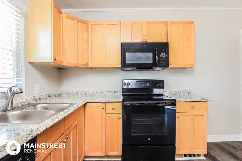 a kitchen with wood cabinets and black appliances and a sink