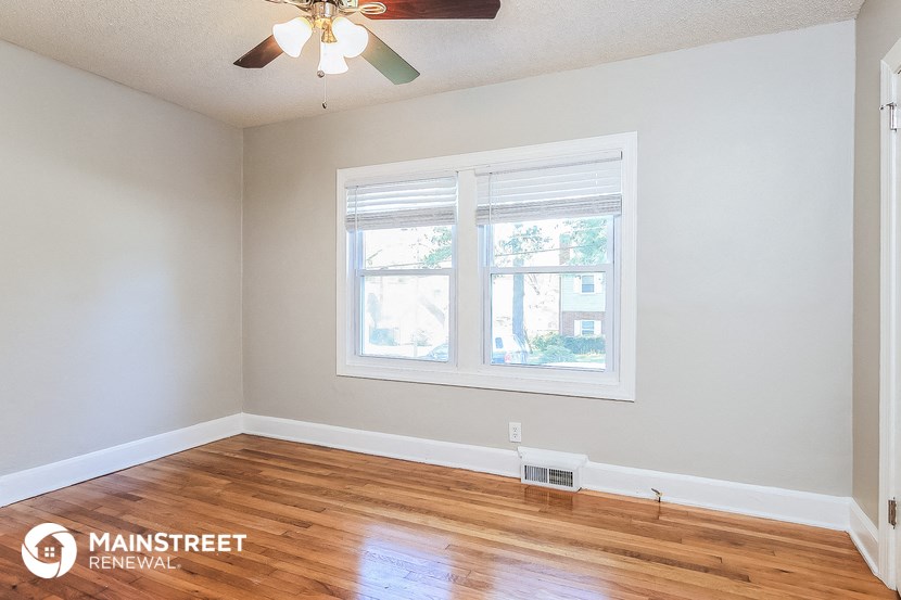 the living room of a home with wood floors and a ceiling fan