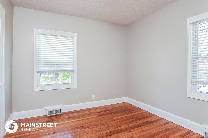 the interior of a room with wood floors and two windows