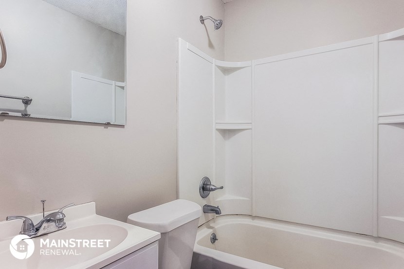 a white bathroom with a tub and a sink and a mirror