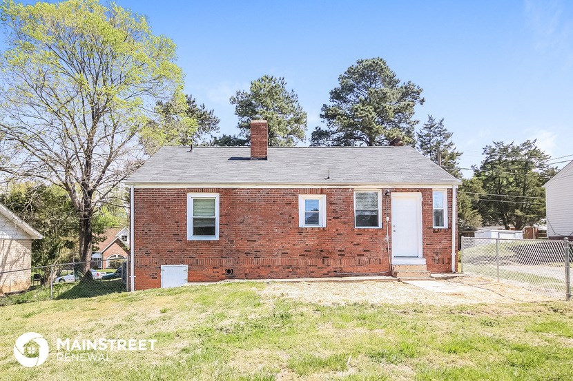 a small brick house with a white door and a yard