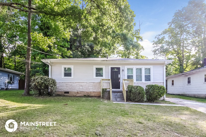 a small white house with a yard and trees
