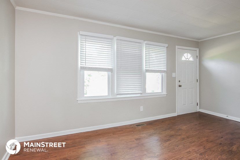 the living room of a home with a wood floor and a white door