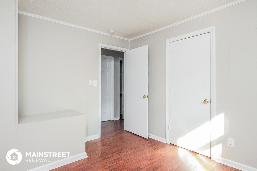 a bedroom with a hard wood floor and white walls