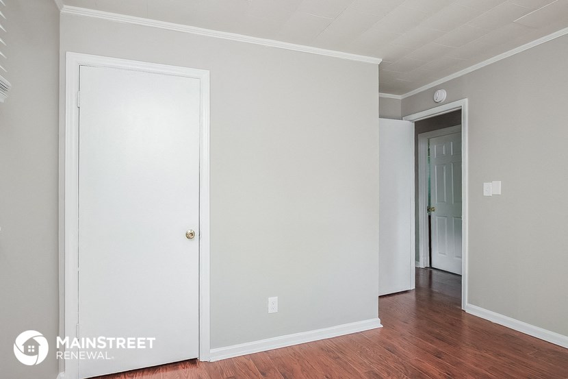 the living room of a house with white walls and a wood floor