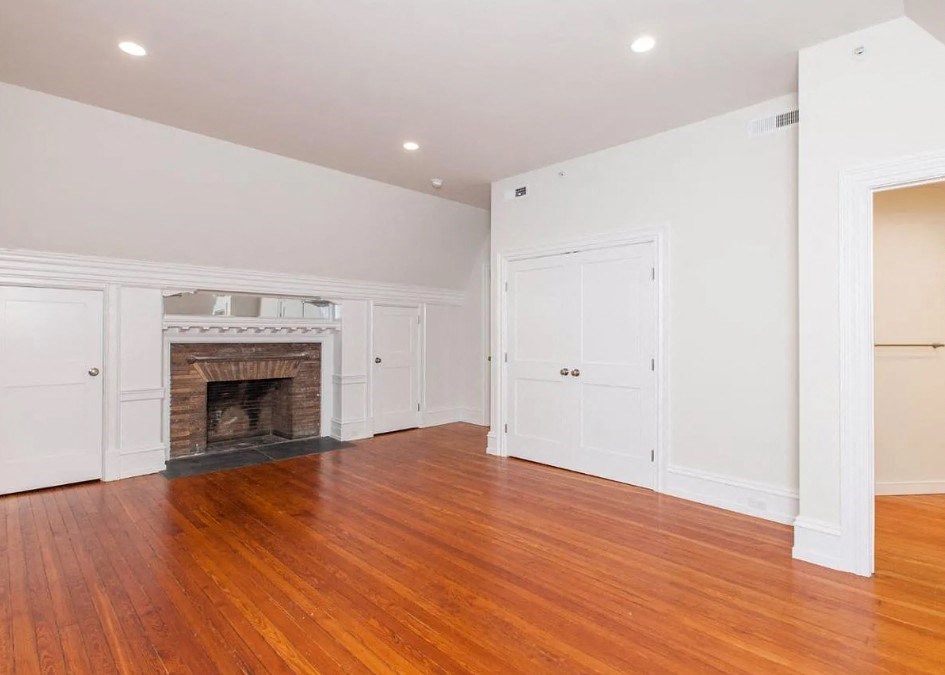 an empty living room with a fireplace and wooden floors