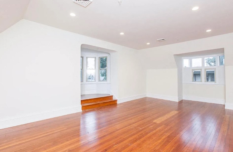 a living room with a hard wood floor and white walls
