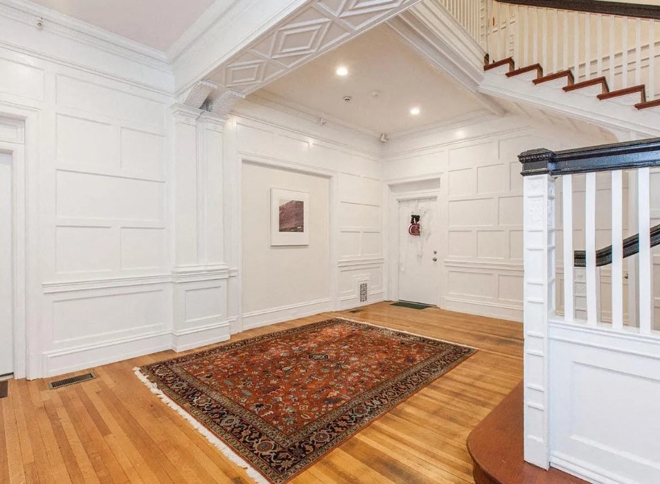 a large white room with a staircase and a rug on the floor