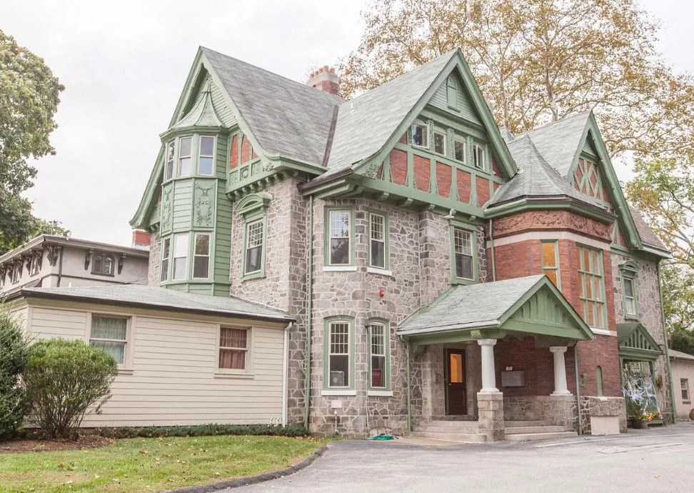 an old house with green and brick and a driveway