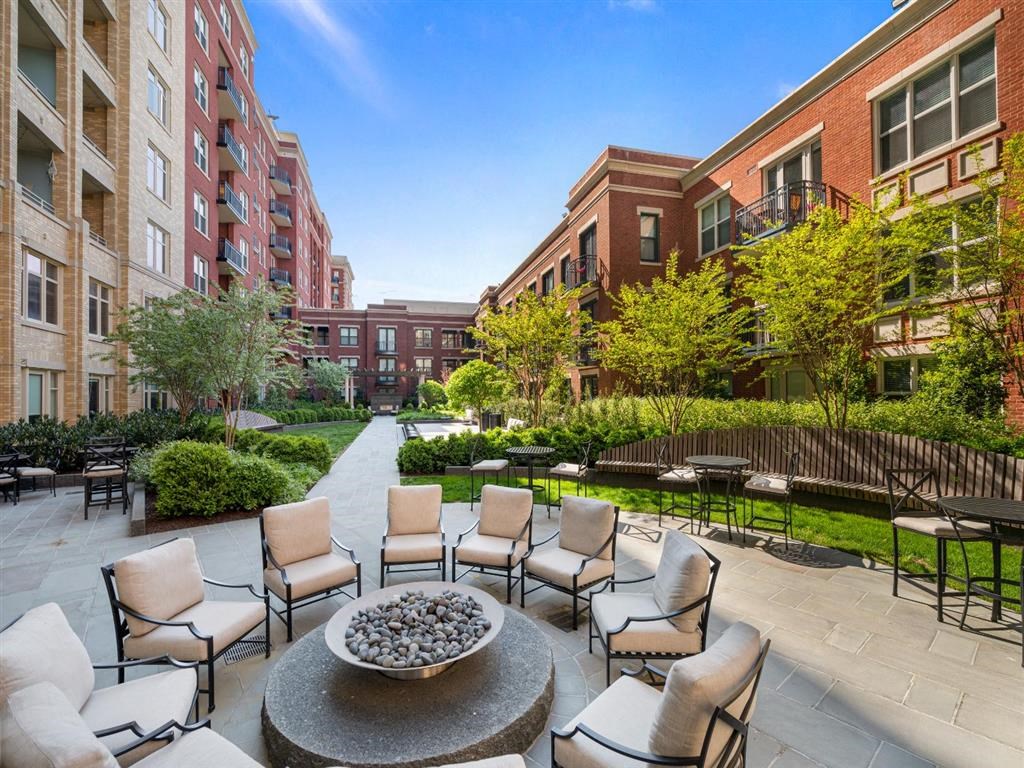 a patio with chairs and a table in a courtyard with buildings