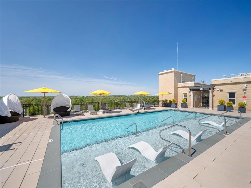 a swimming pool with chairs and a building in the background