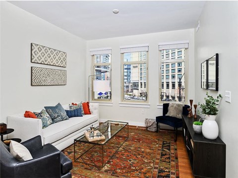 a living room with a couch and a chair and three windows