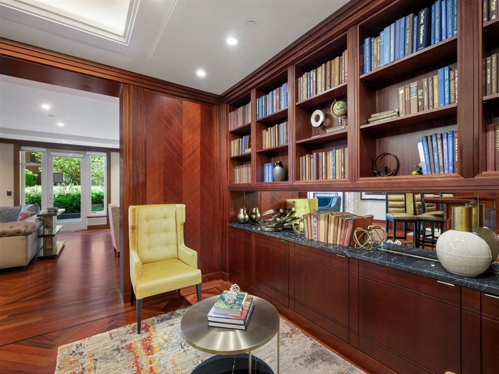 a library with a desk and a yellow chair