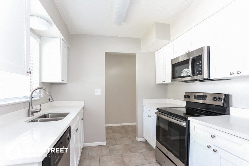a kitchen with white cabinets and black appliances and a sink