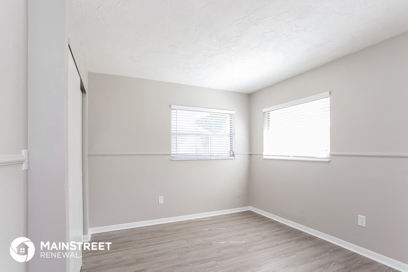 the spacious living room with wood flooring and white walls