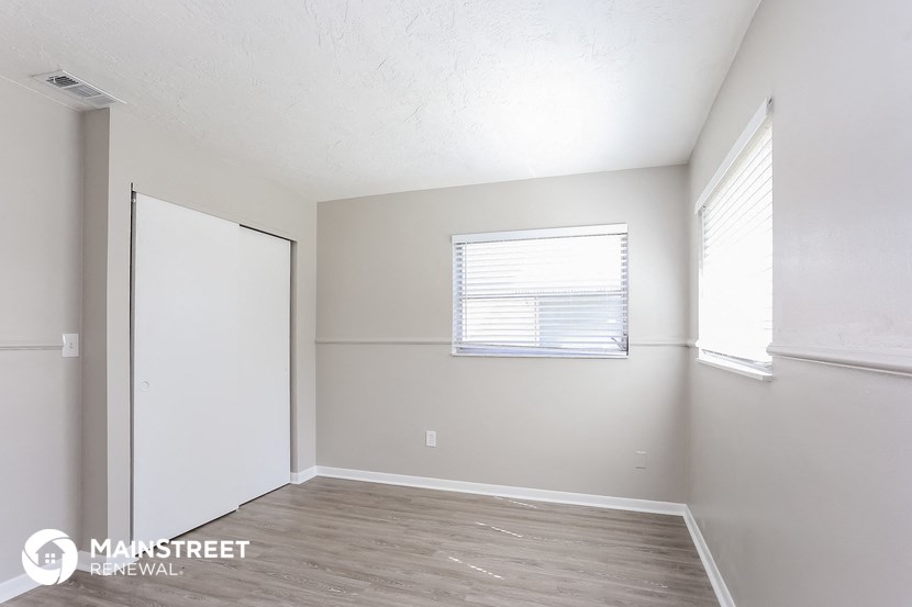 the spacious living room with white walls and wood flooring