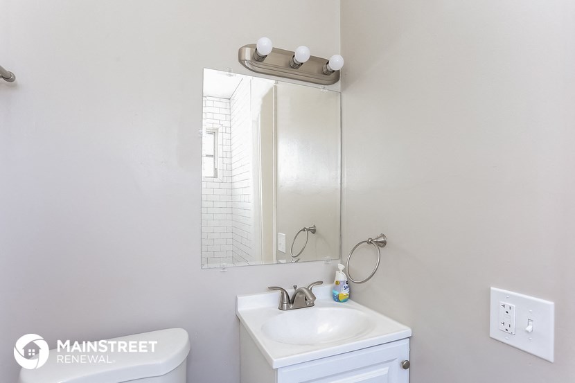 a white bathroom with a sink and a mirror and a white toilet