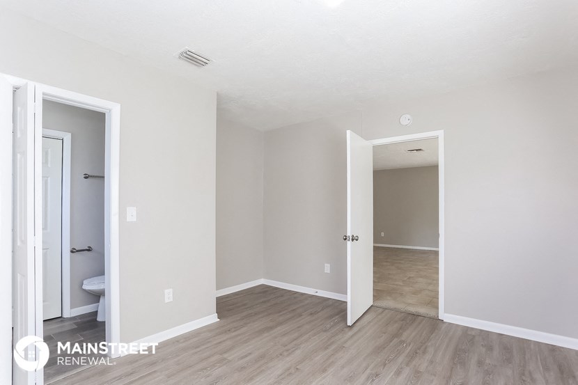 the living room of an apartment with wood floors and white walls