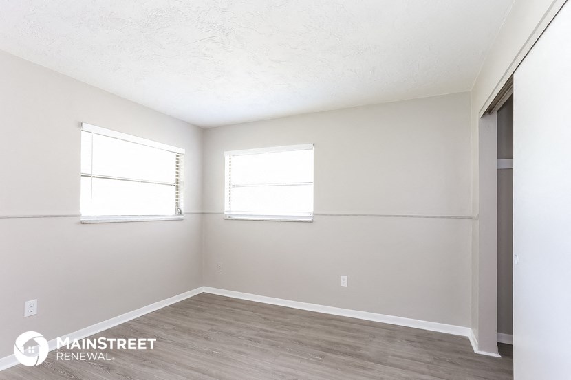 the spacious living room with two windows and wood flooring